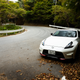 a white nissan fairlady z nismo parked at the edge of a winding mountain road in autumn in japan